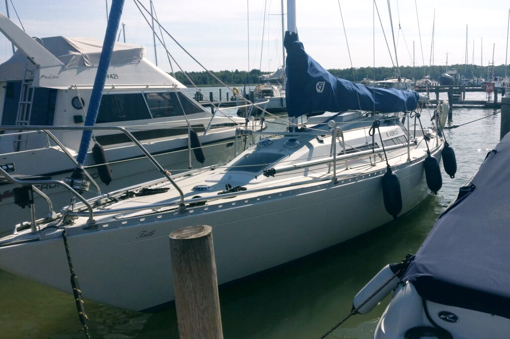 Valkoinen purjevene paalujen välissä laiturissa