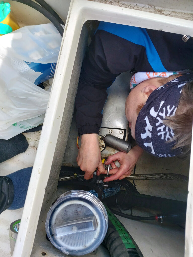 Raakavesisuodatin, tankki ja letkustoa veneen lokerossa