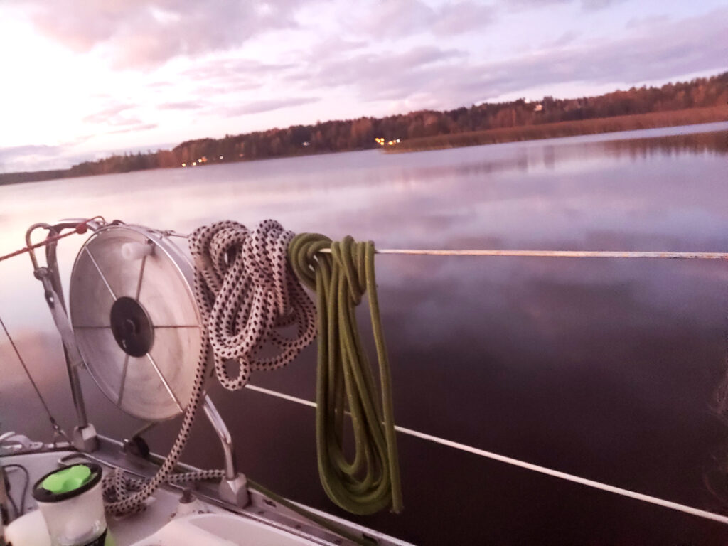 Köysiniput veneen kaiteessa, tyyni meri ja ruskan värjäämä ranta