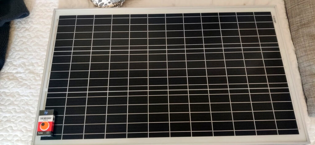 Aurinkopaneeli sohvan päällä. Salmiakkirasia näyttämässä kokoa.