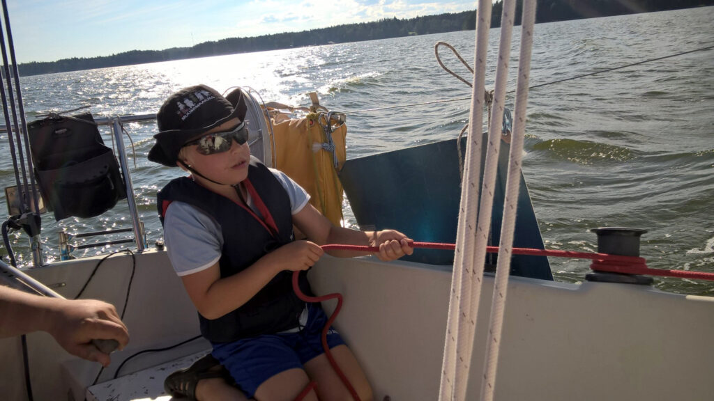 Lapsi pitelee punaisesta köydestä purjeveneessä