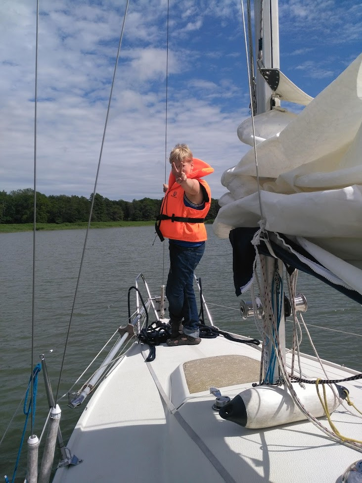 Lapsi näyttää voitonmerkkiä kannella spinnupurjehduksen jälkeen. 