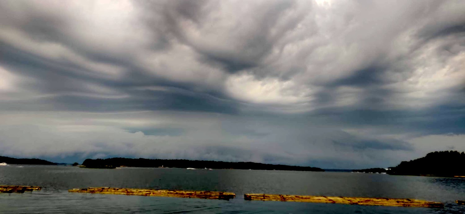 ukkospilvet vyörymässä saaren takaa: varautuminen myrskyyn purjeveneessä on aiheellista.