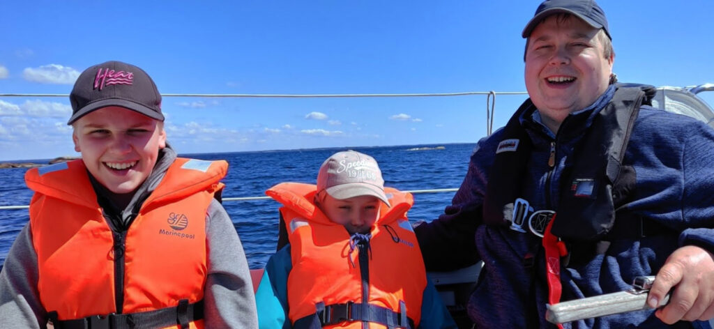 Mies ja kaksi poikaa veneessä