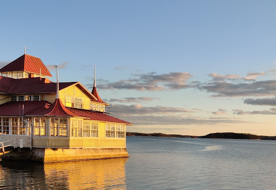 Auringossa hehkuva keltainen rakennus meren äärellä.