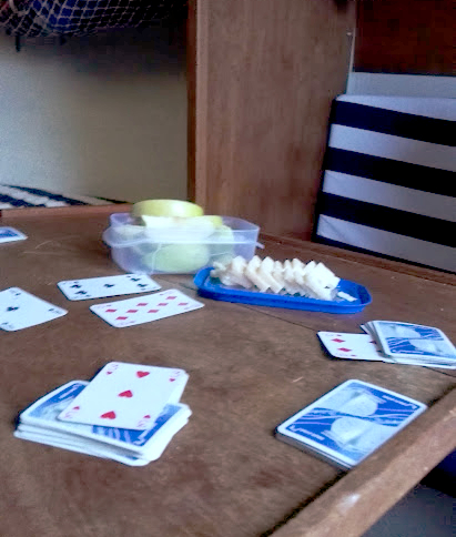 Pelikortit, omenalohkoja ja juustoa venepöydällä 