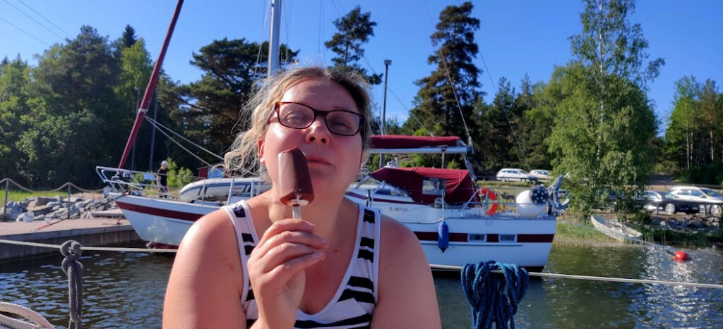 Nainen syö onnellisena jäätelöä auringossa