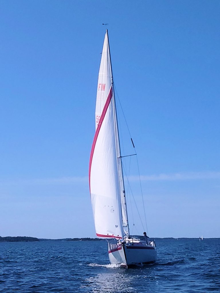 Valkoinen purjevene pujehtii saaristomerellä.